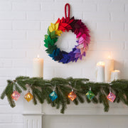 MoMA | LED String Lights Diamond adorn a festive mantel with glowing, faceted ornaments, creating a warm ambiance amid evergreen garland and pillar candles.