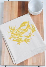 Hearth and Harrow - Set of 4 Organic Cotton Chickadee Cloth Napkins in Yellow, featuring a hand-printed bird design, displayed on a wooden surface.
