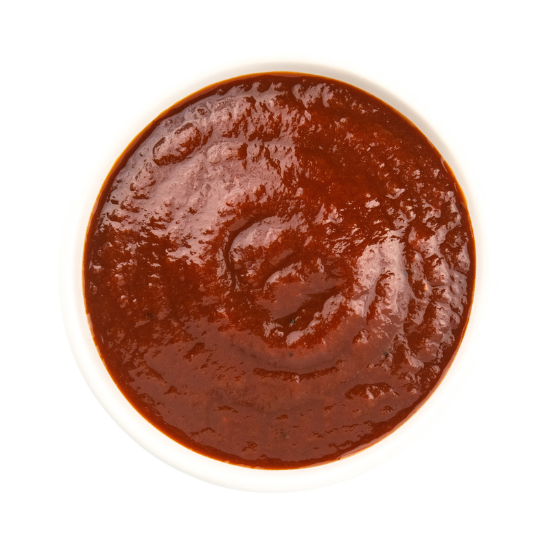 Beth's Farm Kitchen BBQ Sauce in a small white bowl, showcasing its thick, red texture. Ideal for enhancing dishes with its apple-infused smoky flavor.