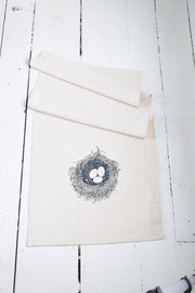 Hearth and Harrow - Nest Tea Towel in organic cotton featuring a navy blue bird's nest design, hand-printed with eco-friendly ink, shown folded.