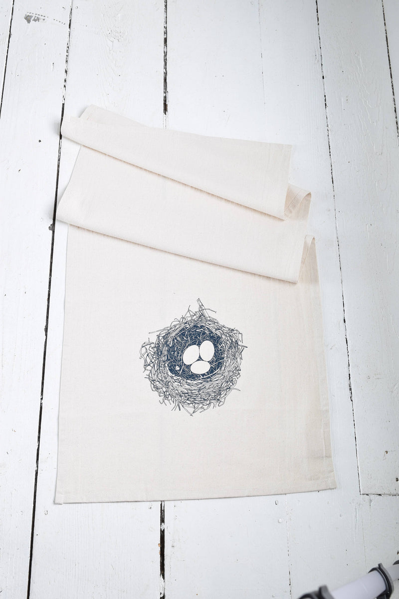 Hearth and Harrow - Nest Tea Towel in organic cotton featuring a navy blue bird's nest design, hand-printed with eco-friendly ink, shown folded.