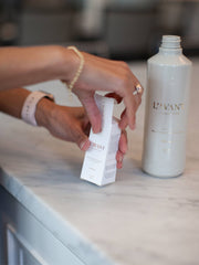 A person opens a white carton to reveal a L'AVANT Collective - Fresh Linen Multipurpose Cleaner Refill, ideal for sustainable kitchen cleaning.
