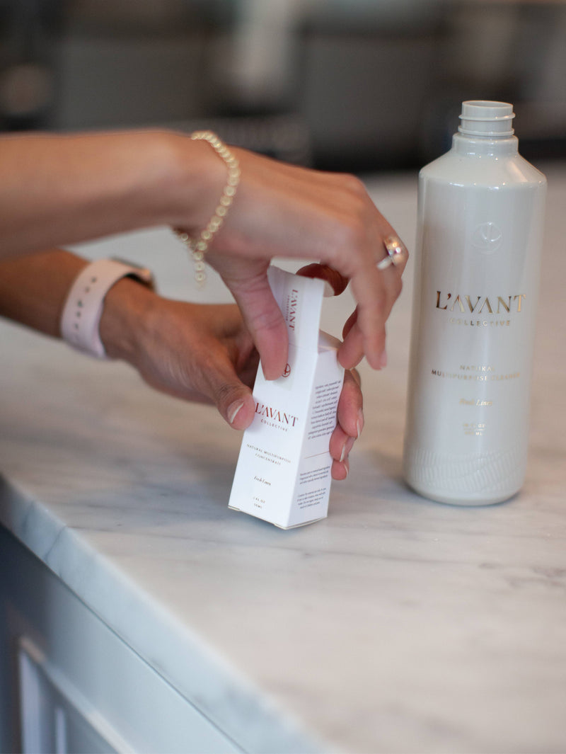 A person opens a white carton to reveal a L'AVANT Collective - Fresh Linen Multipurpose Cleaner Refill, ideal for sustainable kitchen cleaning.