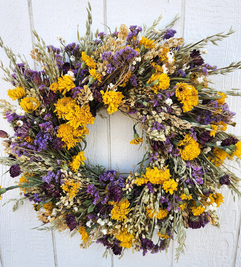 Alissas Flower Farm - Wreath: Spring Rain features yellow marigolds, purple statice, and ammobium, elegantly arranged on pennycress and spring oats.