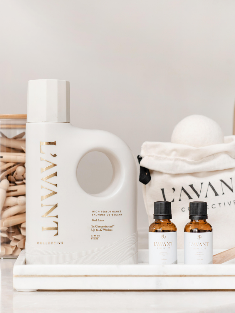 L'AVANT Collective Wool Dryer Balls pack of 3, styled with fragrance oil and clothespins, offering an eco-friendly laundry solution on a marble tray.