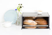 Brabantia USA Inc | Fall Front Bread Box Matt Steel in a kitchen setting, highlighting its space-saving design and easy access lid feature.