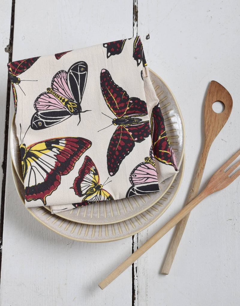 Hearth and Harrow - Butterfly Tea Towel - Organic Cotton - Oversized 30 x 30, folded on ribbed plates with wooden utensils, showcasing its elegant design.