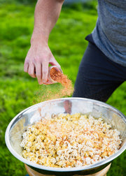 San Juan Island Sea Salt - Kimchi Seasoning Blend sprinkled over popcorn outdoors, showcasing its tangy spice blend with Gochugaru peppers, ginger, and garlic.