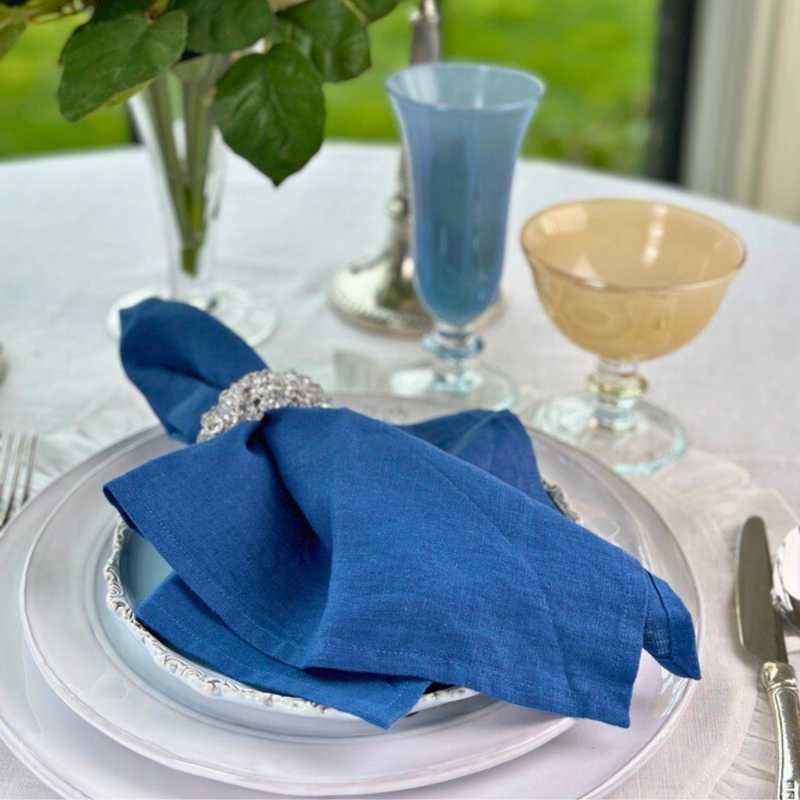 Crown Linen Designs | Washed Linen Napkin Sets - Harvest Gold elegantly displayed on a dining table with glassware and a decorative plate.