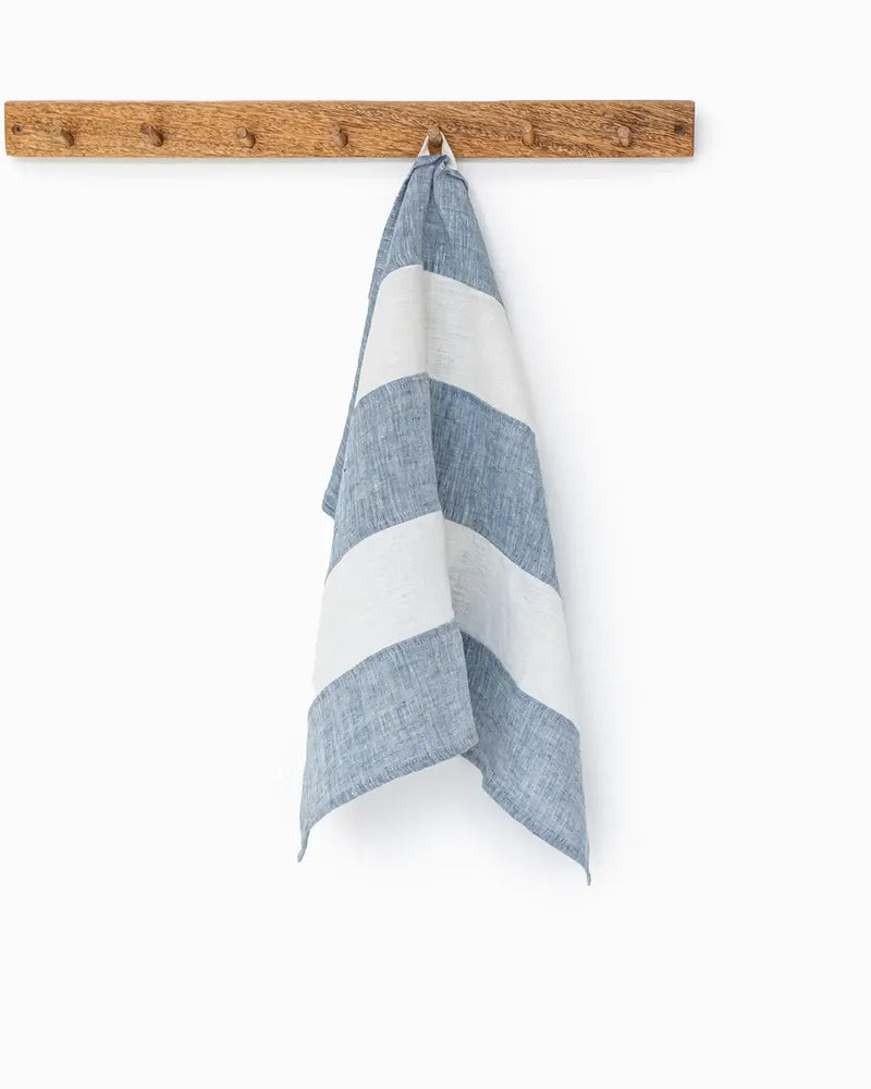 Striped linen tea towel hanging on a hook, showcasing its durable, absorbent texture and practical loop feature, ideal for kitchen use. Part of MagicLinen's zero-waste collection.