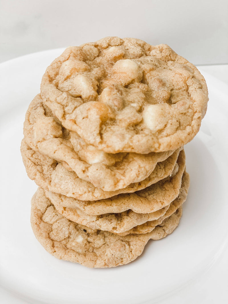Southern Roots Sisters - White Chocolate Snickerdoodle Cookie Mix displayed as freshly-baked, golden-brown cookies with white chocolate chips on a white plate.