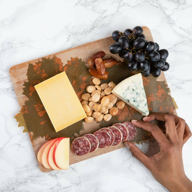Formaticum | Cheese Board Liners - Large displayed with grapes on a cutting board, highlighting their elegant grape leaf design for enhancing culinary presentations.