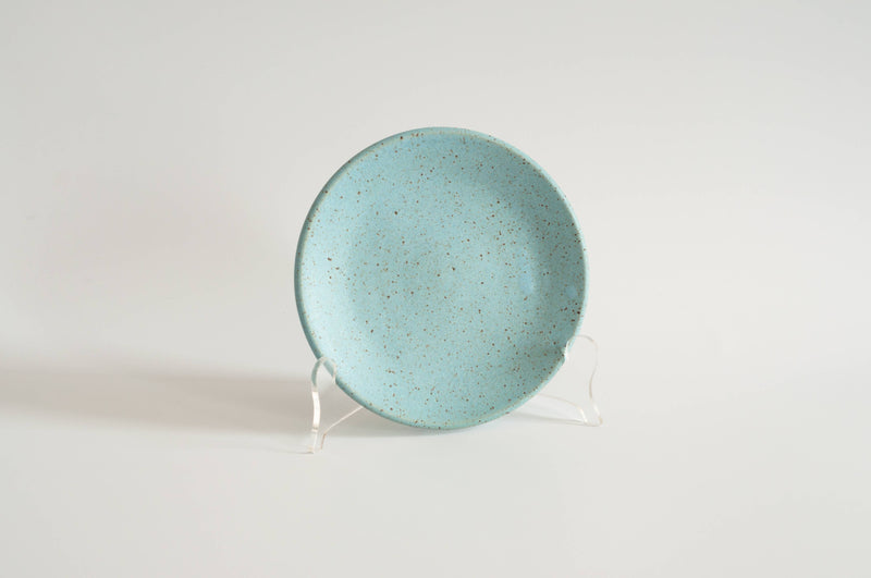 RachaelPots - Dessert Plate: Sage, a hand-thrown, speckled turquoise ceramic plate with a subtle upturned lip, displayed on a stand. Ideal for desserts.