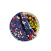 Bee's Wrap - Assorted 3 Pack - Botanical partially covers a bamboo bowl with salad greens, showcasing its reusable, eco-friendly food storage wrap with bird and floral prints.