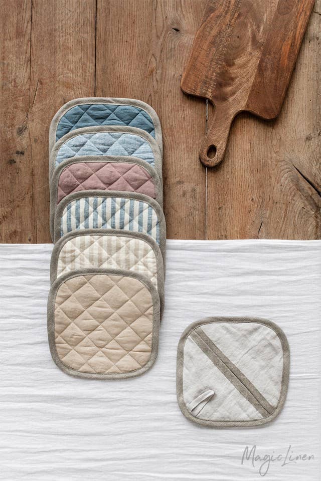 MagicLinen - Linen pot-holder on a wooden table, showcasing quilted detailing and a hanging loop, perfect for heat protection while cooking.