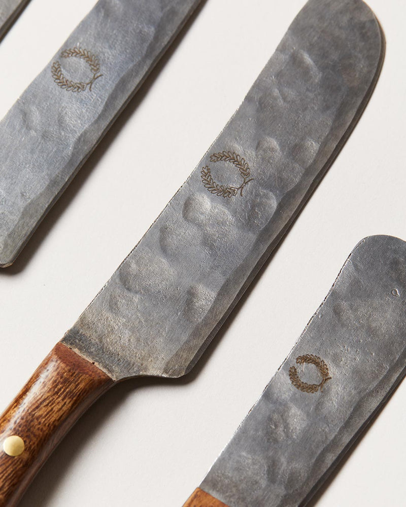 Farmhouse Pottery | Artisan Forged Cheese Knives featuring hammered-steel blades with wreath motifs and smooth wooden handles, perfect for rustic kitchen settings from Athens Cooks.