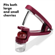 OXO Good Grips Cherry & Olive Pitter in Beet, shown in a plastic container, features a non-slip grip and splatter shield for easy, mess-free pitting.