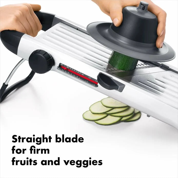 Person using the OXO Chef's Steel Mandoline to slice zucchini, showcasing its efficient design as a kitchen tool.