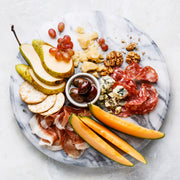 White Marble Lazy Susan showcasing a charcuterie spread with fruits, cheeses, meats, olives, walnuts, and crackers; perfect for effortless, elegant entertaining.