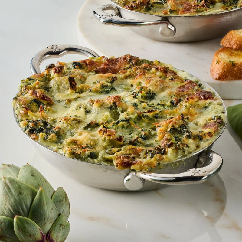 Hestan Provisions | Chef's Special Oval Clad Au Gratin showcasing hot spinach-artichoke dip, served with crostini and a raw artichoke, ideal for gourmet kitchen experiences.