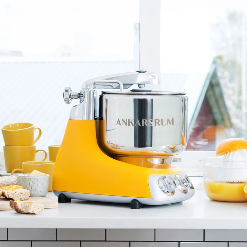 Ankarsrum stand mixer in a kitchen scene with bread and citrus juicer, embodying Athens Cooks' focus on quality, versatile kitchen tools for baking and cooking.