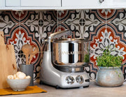Ankarsrum stand mixer on a kitchen countertop with accessories, surrounded by cooking essentials, embodying Athens Cooks' dedication to quality kitchen tools.