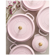 Overhead view of Staub Round Dutch Oven, Pink Peony, 7 QT, featuring enameled cast-iron pots with brass knobs and embossed lids, accented by delicate pink flowers.