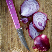 Opinel | Essential Birdsbeak Vegetable Knife - Pink on wooden board with sliced red onion, showcasing its precision cutting and ergonomic handle for versatile kitchen use.