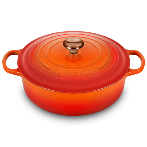 Le Creuset Signature Round Wide Oven in Flame, a 6.75-quart enameled cast-iron Dutch oven with side handles and a tight-fitting lid, ideal for versatile cooking.