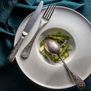 Christofle | 5-Piece Place Setting Jardin d'Eden Silver Plated with engraved floral utensils on a bowl of sliced vegetables, showcasing elegant, nature-inspired dining.