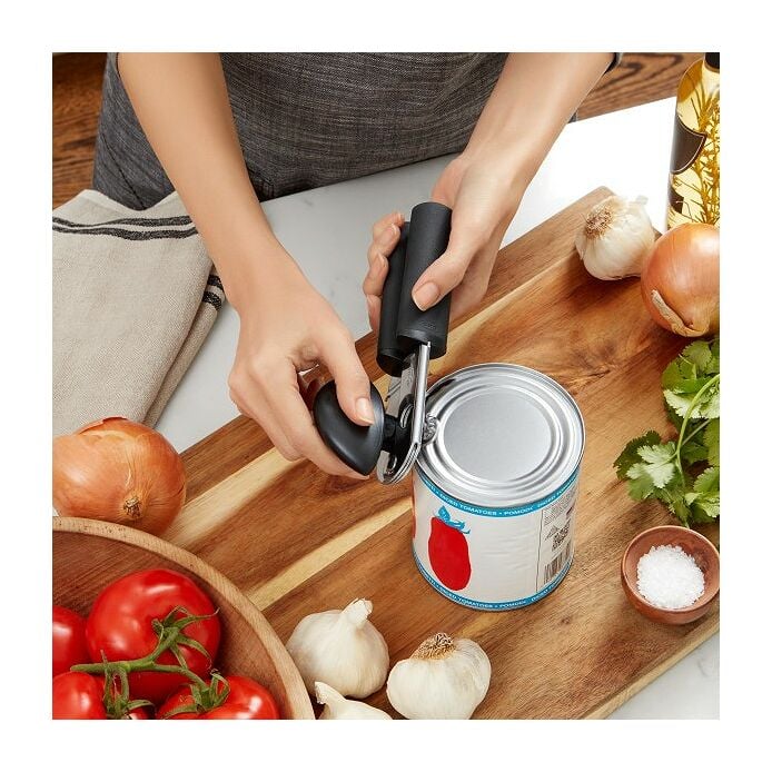 OXO Soft-Handled Can Opener in use, showcasing its ergonomic design with cushioned handles and oversized knob, ideal for effortless can opening in the kitchen.