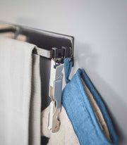 Yamazaki Home | Magnetic Kitchen Towel Hanger, Steel, White: Wall-mounted towel hanger with a black hook holding a stainless-steel clamp and blue linen fabric.