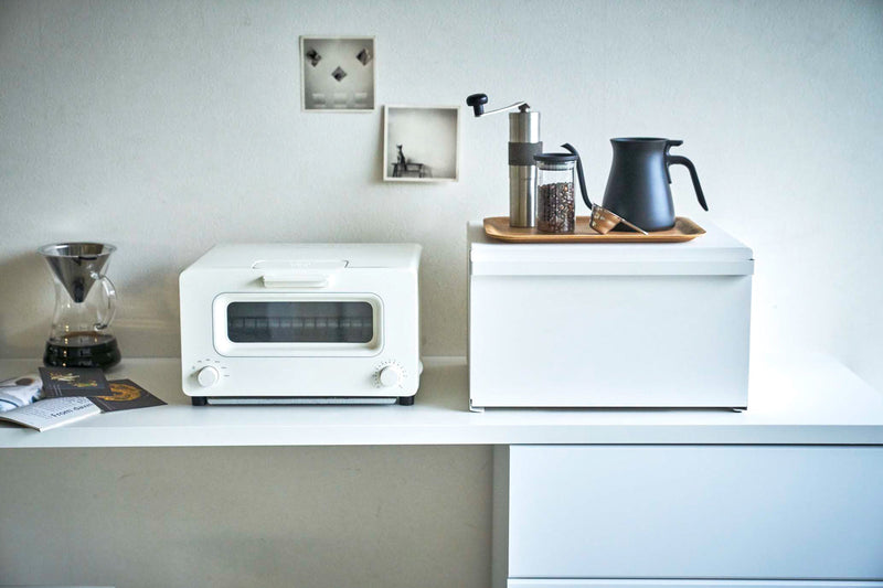 Minimalist counter featuring Yamazaki Home | Tower Bread Box, Steel, Black, beside a toaster-oven, Chemex, coffee grinder set, emphasizing sleek kitchen organization.
