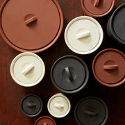 Sir|Madam Terra Cotta Larder Crock No. 10 with lid, inspired by French design, shown among other crocks on a wooden surface.