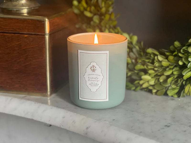 Lodestone Candles | Linden & Heliotrope Candle on a marble surface, next to a box, offering floral citrus and vanilla scents with 80-hour burn time.