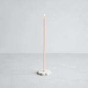 The Floral Society | Long Stem Beeswax Candle in pale pink, elegantly set in a white flower-shaped holder, offering a warm, minimalist glow for intimate settings.