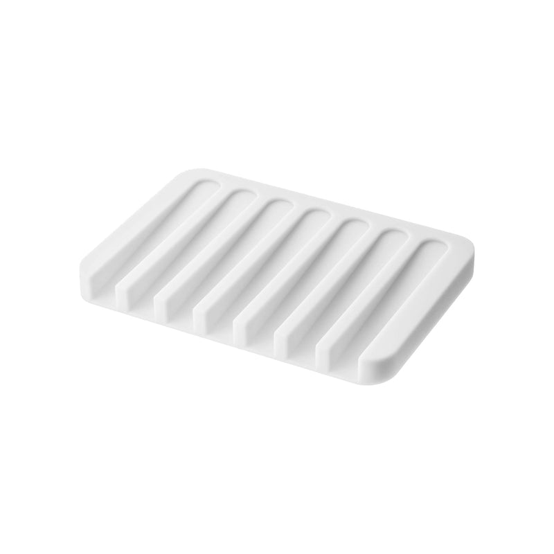 Yamazaki Home | Flow Self-Draining Soap Tray: A sleek, white silicone soap dish with raised ridges, designed to keep soap dry and counters clean.