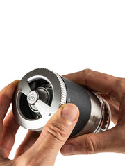 Hands holding the Peugeot Maestro Pepper Bar, showcasing its metal body, black grip, and exposed burr-grinding mechanism.