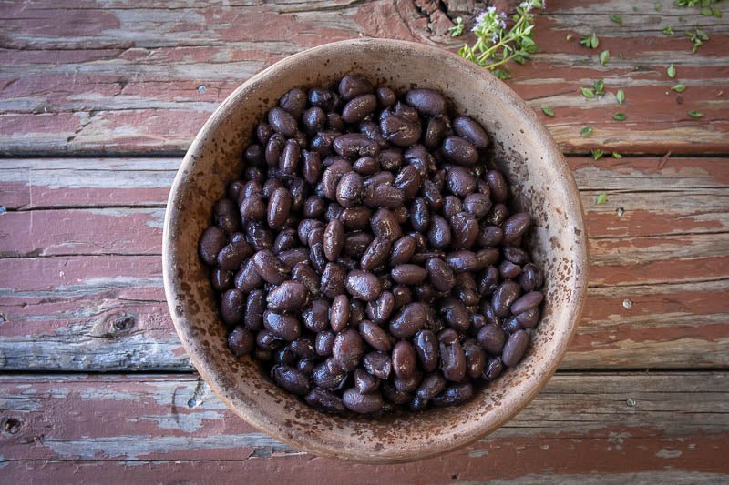 Rancho Gordo | Midnight Black Bean in a bowl on a wooden surface, showcasing its rich texture and culinary versatility for Athens Cooks' specialty food selection.
