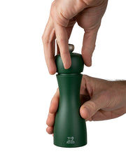 Hands twist open a dark-green Peugeot Tahiti Duo Pepper Mill. The manual grinder, part of a sophisticated set, is ideal for kitchen enthusiasts.