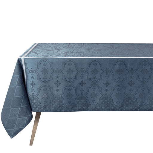Le Jacquard Francais | Armoiries Tablecloth, Blue, 69 x 98 drapes elegantly over a table, showcasing a raised quatre-foil and floral damask pattern.