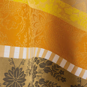 Le Jacquard Francais Gipsy Tablecloth, Yellow, 69 x 98 featuring warm-toned floral and leaf motifs in a luxurious jacquard weave, ideal for an elegant, bohemian-inspired setting.
