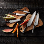 Shun Narukami 8 Chef's Knife displayed with fruit slices on cutting boards, showcasing its polished steel blade and dark handle, ideal for professional cooking tasks.