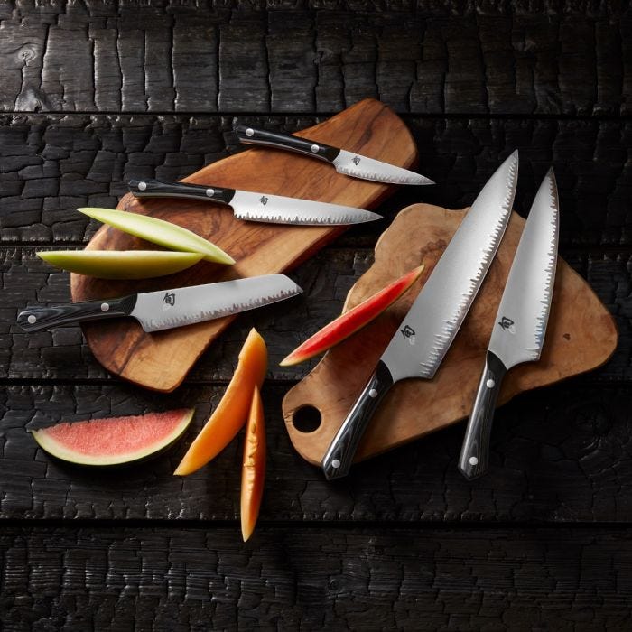 Shun Narukami 8 Chef's Knife displayed with fruit slices on cutting boards, showcasing its polished steel blade and dark handle, ideal for professional cooking tasks.