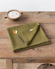 MagicLinen's 59 x 98-inch olive green linen tablecloth, featuring a simple seam finish, perfect for enhancing dining settings at Athens Cooks.