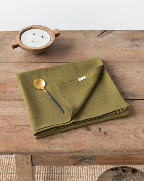 MagicLinen's 59 x 98-inch olive green linen tablecloth, featuring a simple seam finish, perfect for enhancing dining settings at Athens Cooks.