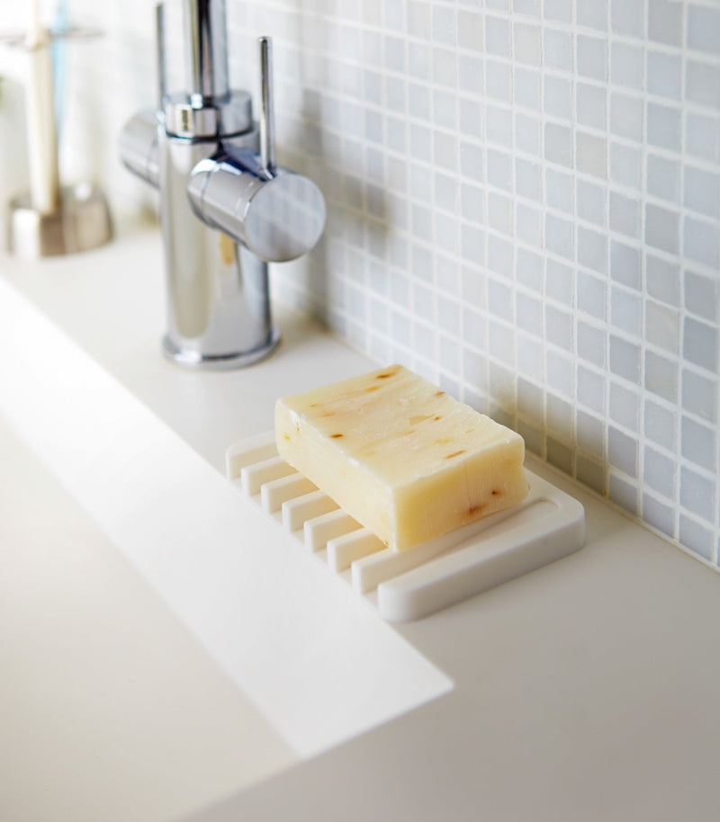 Yamazaki Home | Flow Self-Draining Soap Tray in silicone, displayed with a homemade-style soap bar on a sleek bathroom sink.