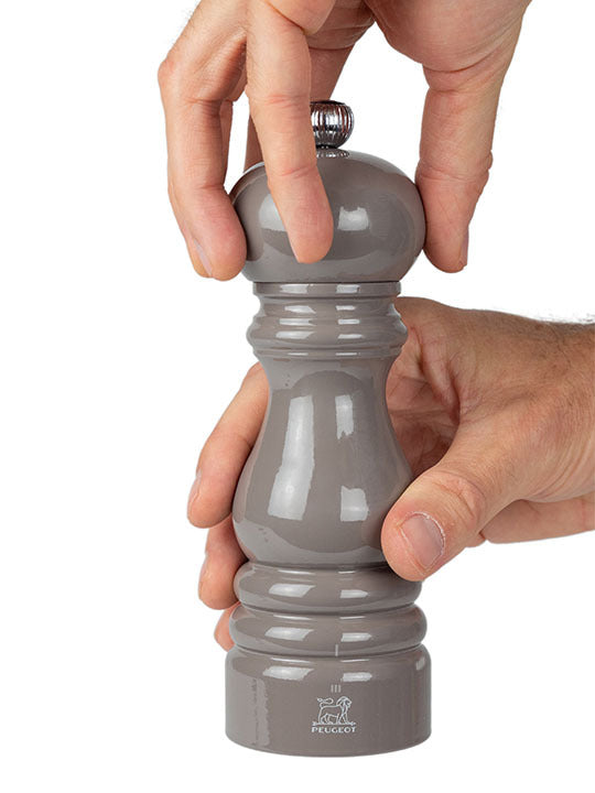 Hands twist the Peugeot Paris U'Select Pepper Mill, Taupe, showcasing its glossy finish and precise grind control, embodying elegance and functionality from Athens Cooks.