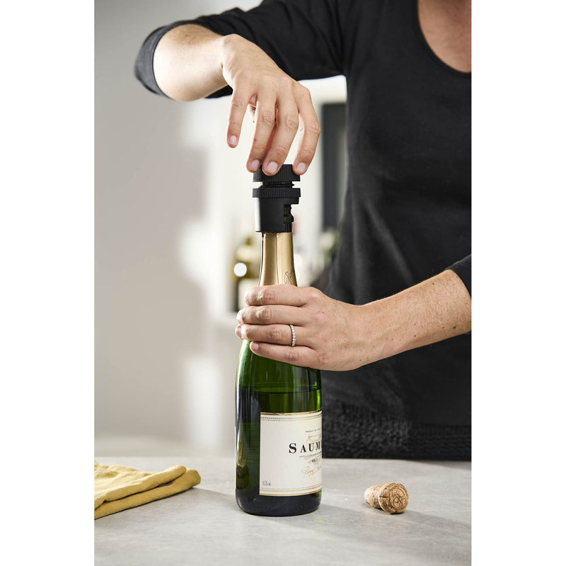 Peugeot | Preserve Champagne Stopper being used by a person to open a champagne bottle, highlighting its functionality in maintaining freshness.