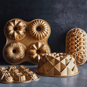 Nordic Ware | Mini Bundt Charms Pan featuring six intricate Bundt shapes for versatile baking, ideal for cakes, brownies, and more, showcased in gold molds.